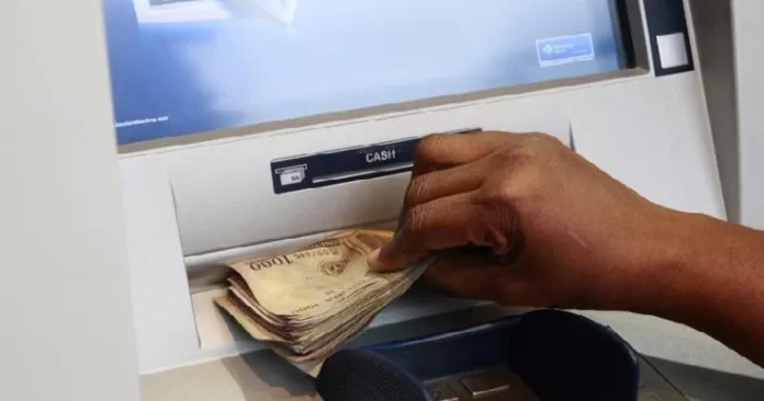 A woman takes Nigerian Naira from a bank's automated teller machine (ATM) in Ikeja district in the commercial capital Lagos